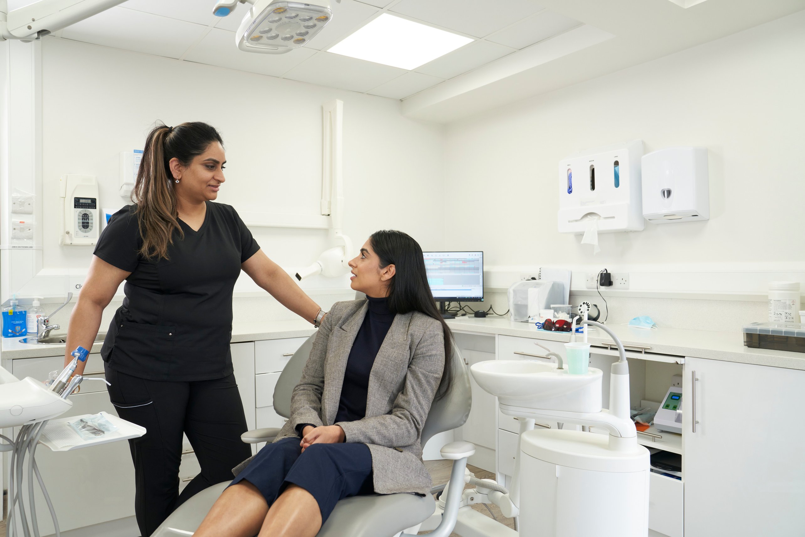 Indian dentist and patient in a modern dental surgery. The dentist talks to the patient and smiles